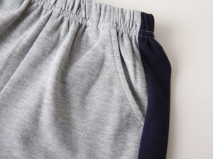 Detailed close-up of elastic waistband and pocket stitching on boy's grey cotton shorts
