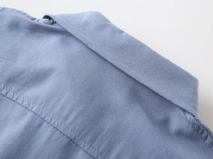 Detail of light blue cotton shirt fabric texture and stitching on the collar and shoulder