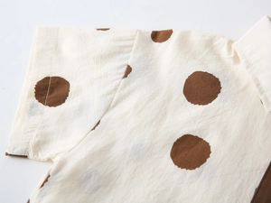 Detail shot of white cotton shirt with large brown dots showing smooth seam and texture