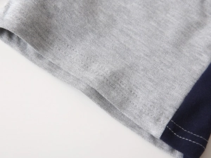 Close-up of grey pique polo shirt sleeve with navy blue trim and fine stitching detail