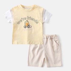 Detail of yellow toddler t-shirt with dinosaur car print and matching beige shorts