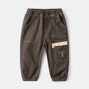Detail of brown kids cargo pants with contrast stitching and cartoon pocket embroidery