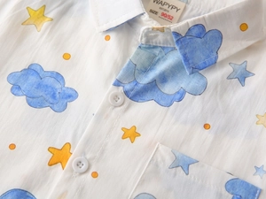 Close-up of kids cotton shirt featuring watercolor blue clouds and yellow star patterns