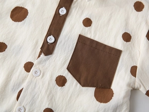 Detail of baby summer shirt with brown polka dots, wooden buttons and contrast pocket