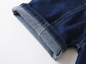 Gros plan détaillé du short en denim bleu foncé avec ourlets roulés et doubles coutures