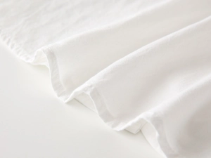 Close-up of white cotton linen fabric with detailed hem stitching for kids shirt