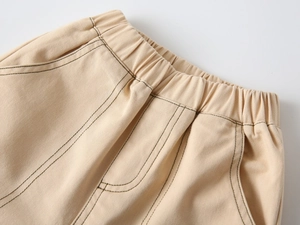 Detailed close-up of elastic waistband and contrast stitching on khaki cotton trousers