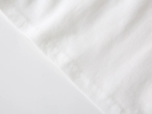 Close-up of double-stitched hem on a white cotton polo shirt showing fabric texture