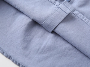 Detailed close-up of light blue cotton shirt hem showing fine twill texture and stitching