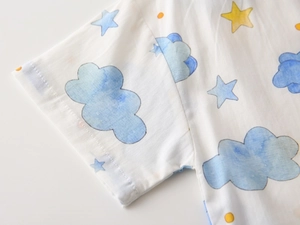 Close-up of soft white cotton shirt showing blue clouds and yellow stars print detail