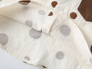 Close-up of cotton linen boy shirt featuring brown dots and premium button stitching