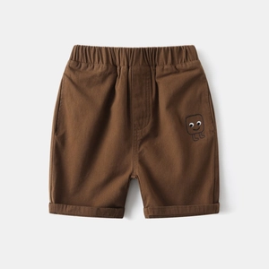Detail of brown cotton kids shorts featuring elastic waist and smile face embroidery