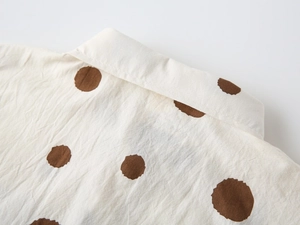 Detail of boys' beige polka dot shirt featuring cotton-linen texture and classic collar