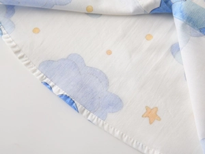 Close-up of cotton baby shirt fabric with blue clouds and yellow star patterns