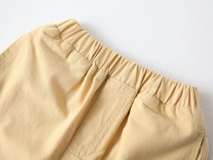 Detailed macro view of the elastic waistband on khaki cotton twill shorts for boys