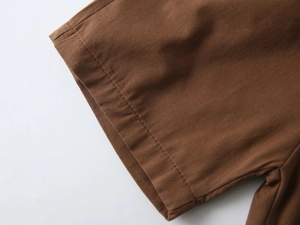 Close-up of brown cotton twill fabric showing neat double-row stitching on sleeve cuffs