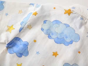Detail of soft cotton kids shirt fabric with blue clouds and yellow stars pattern