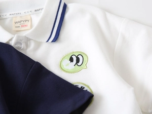 Détail d'un polo blanc pour garçon montrant la texture en coton piqué et la broderie