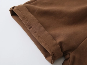 Macro detail of brown cotton fabric showing double-stitched hem and fine texture