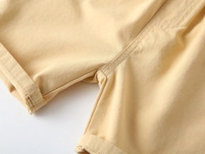 Close-up of light yellow cotton shorts showing rolled cuffs and precise stitching details
