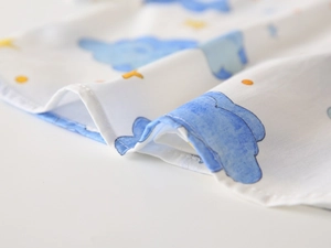 Close-up of soft white fabric with blue watercolor clouds and yellow star print for kids