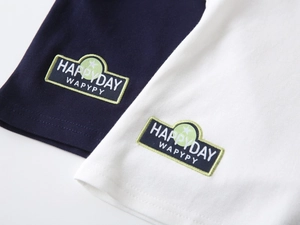 Gros plan détaillé du tissu polo avec écusson brodé HAPPYDAY pour vêtements de garçons
