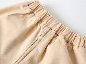 Detail of children's beige cotton joggers featuring a durable elastic waistband with stitching