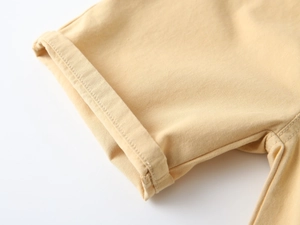 Macro shot of folded cuffs and reinforced stitching on yellow cotton shorts