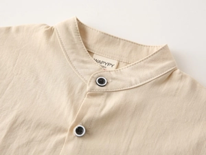 Close-up of cream cotton linen boys shirt with contrast buttons and high-quality stitching