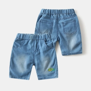 Detail of light blue denim shorts featuring elastic waist and dinosaur embroidery