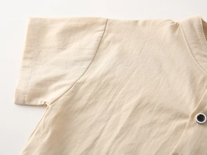 Detailed macro view of beige linen fabric texture and fine stitching on a boy's shirt