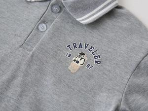 Gros plan du polo gris pour garçon avec broderie d'ours et texture en maille piquée