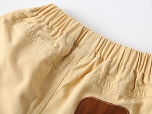Detail of boys' khaki cotton shorts featuring elastic waist and reinforced double stitching