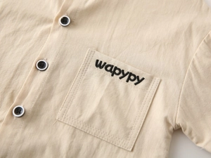 Detail of boys v-neck shirt with contrast buttons and wapypy embroidered pocket