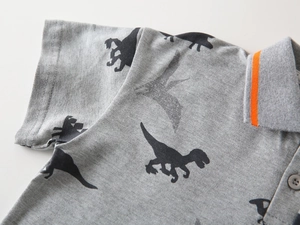 Close-up of grey kids polo shirt featuring dinosaur prints and orange striped collar