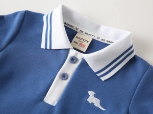 Close-up of boys' blue piqué cotton polo shirt with white collar and dog embroidery
