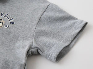 Détail d'un polo en coton piqué gris avec motif traveler et couture à la manche