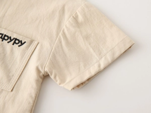 Close-up of beige boys' V-neck shirt showing cotton fabric texture and pocket embroidery