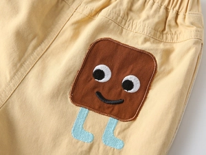 Detail of kids cotton shorts featuring elastic waist and cute cartoon character patch