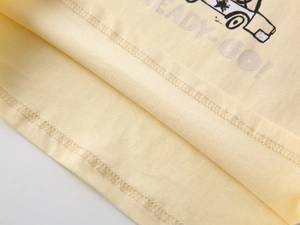 Detailed macro view of the double-stitched hem and soft cotton fabric on boys' yellow t-shirt