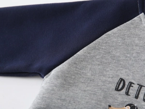 Close-up of raglan sleeve stitching on navy and grey kids sweatshirt with print