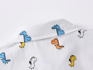 Detail of baby boys white shirt collar with colorful cartoon dinosaur prints and soft twill fabric