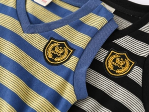 Detail shot of V-neck knitted vests featuring striped patterns and embroidered badges