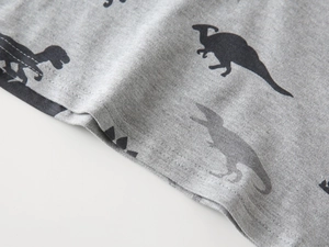 Detailed view of the double-stitched hem and black dinosaur prints on gray polo shirt