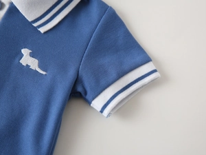 Close-up of boys blue cotton polo shirt with white dachshund embroidery on chest