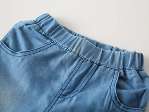 Detail of the elastic waistband and side pockets on light blue denim kids shorts