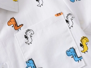 Close-up of boys' white cotton shirt showing colorful dinosaur print and pocket detail