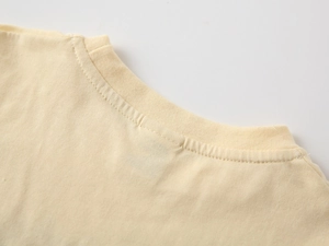 Detail of baby boy cotton t-shirt showing ribbed crew neck and fine stitching in beige