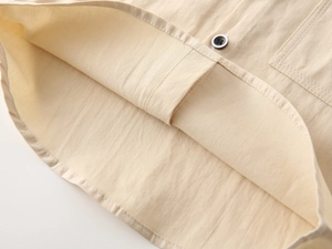 Close-up of boys' beige cotton shirt showing curved hem and neat stitching details