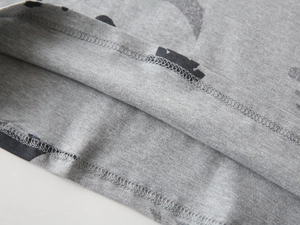 Macro detail of the double-needle stitched hem and bat print on gray knit cotton fabric
